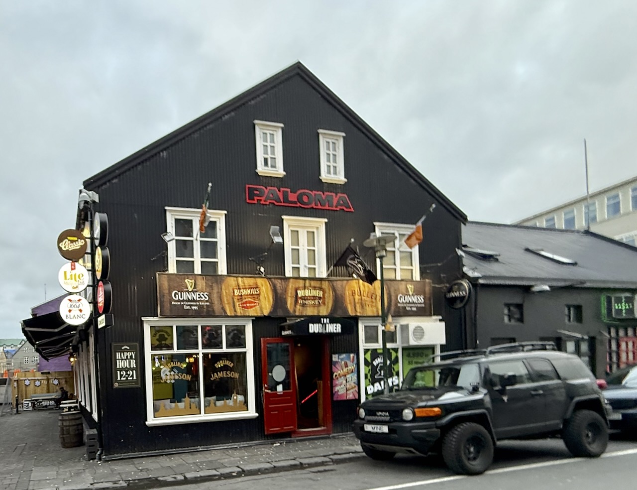 the-dubliner-bar-naustin-reykjavik-Iceland - 1 mynd af Litla Dubliner, írskum bar við Frakkastíg 9 í Reykjavík. Húsið er skreytt litríku veggjaklæði með öldum og sjávarþema, ásamt merkjum fyrir bjórtegundir eins og Gull, Lite, Boli, Blanc og Guinness. Viðarveröndin fyrir framan húsið er skreytt blómakerjum og merkingum staðarins